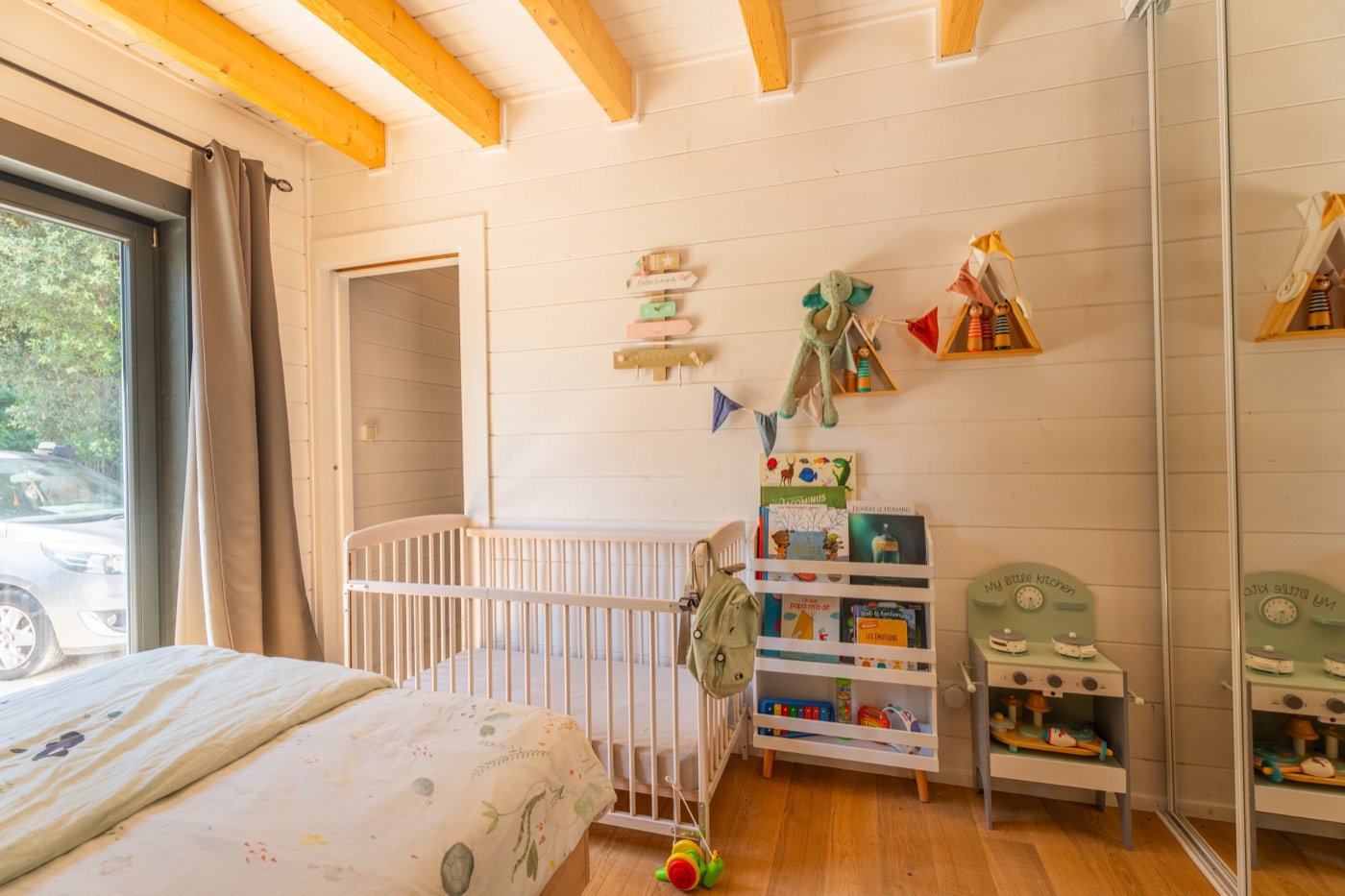 Chambre du rez-de-chaussée avec lit double 140 cm, murs en lambris blanc et accès direct à la terrasse