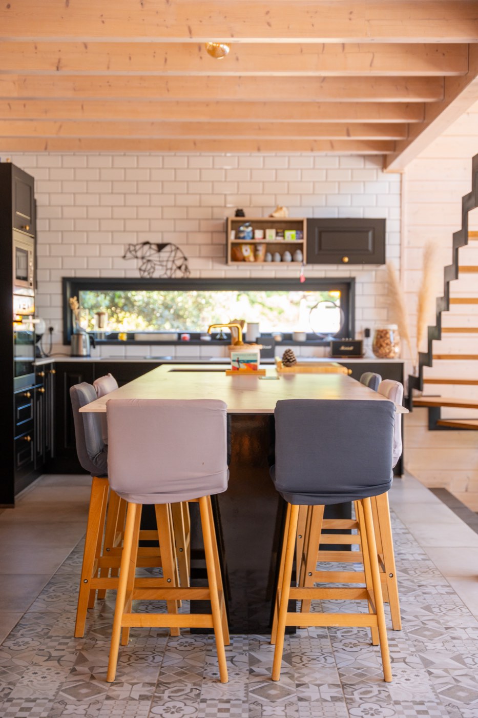 Cuisine équipée du Chalet Moana avec façades noires, crédence en carreaux métro, plan de travail marbré et robinetterie dorée