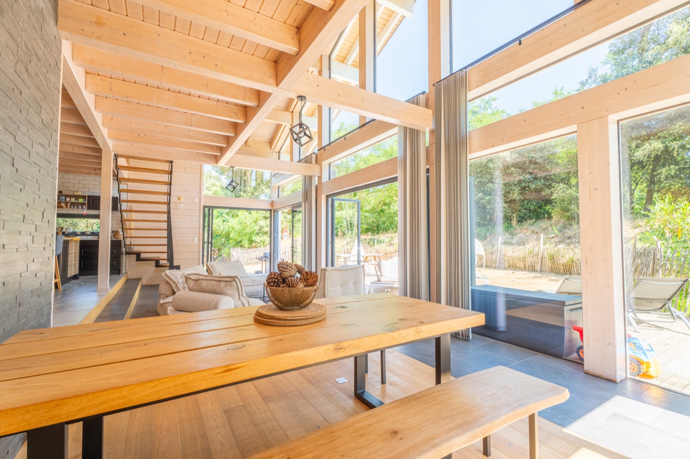 Salle à manger avec grande table en bois massif et bancs, ouverte sur la terrasse du Chalet Moana