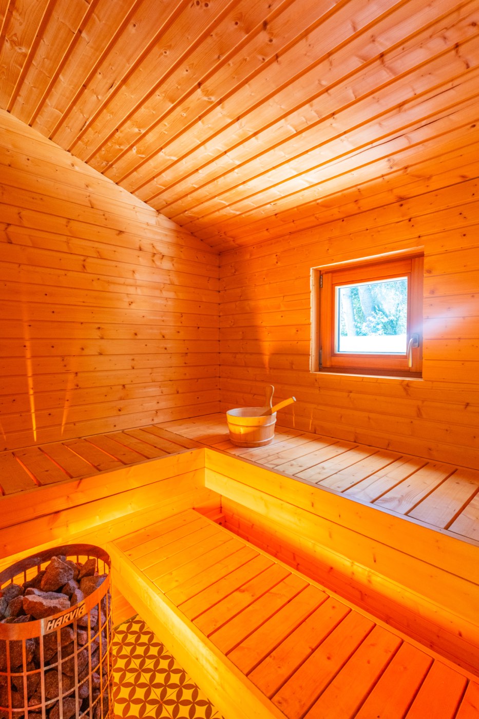 Sauna finlandais privatif en bois clair avec banquettes et petite fenêtre sur la forêt, Le Chalet Moana
