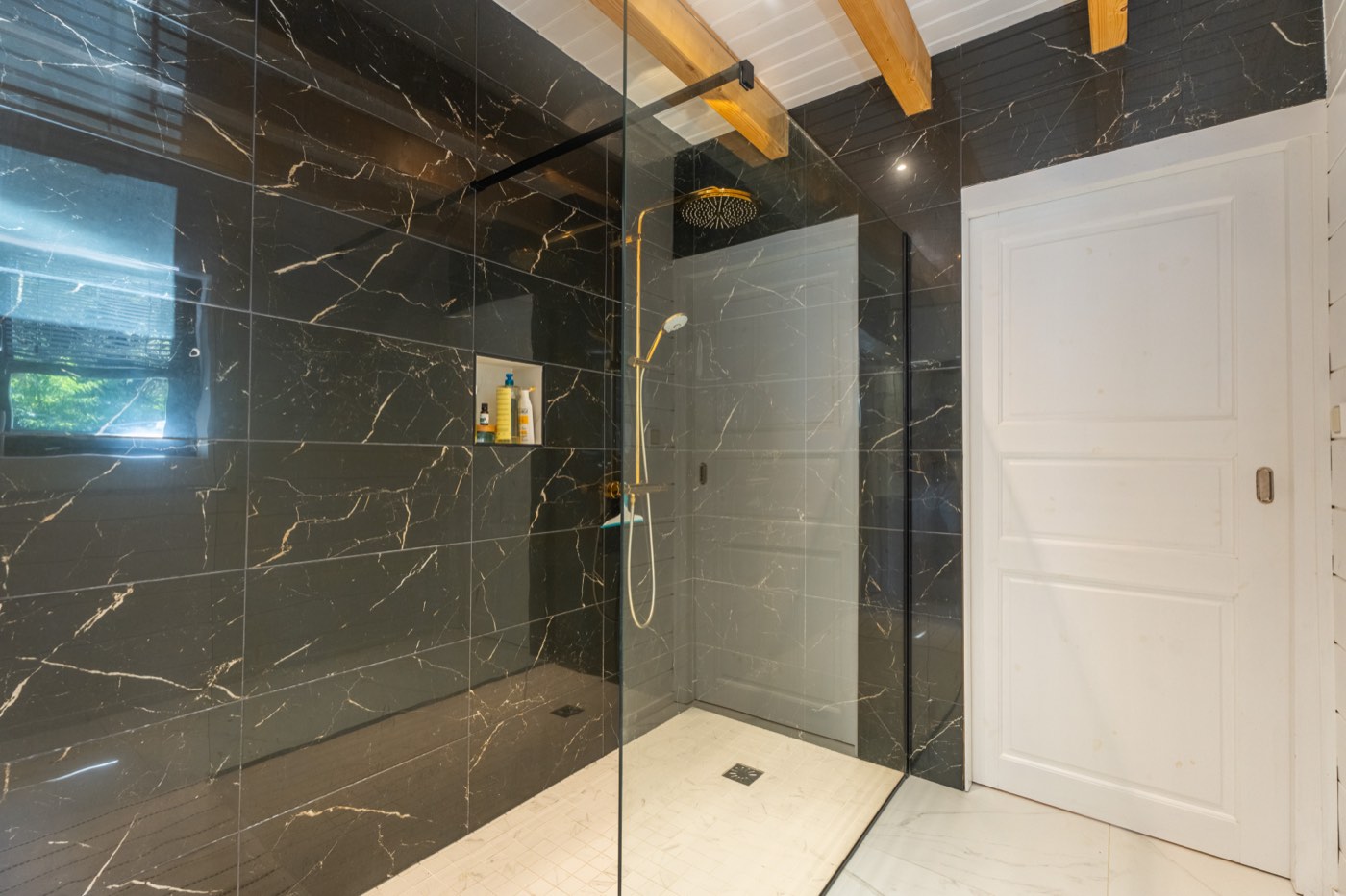Salle de bains du rez-de-chaussée avec douche à l'italienne en marbre noir et robinetterie dorée