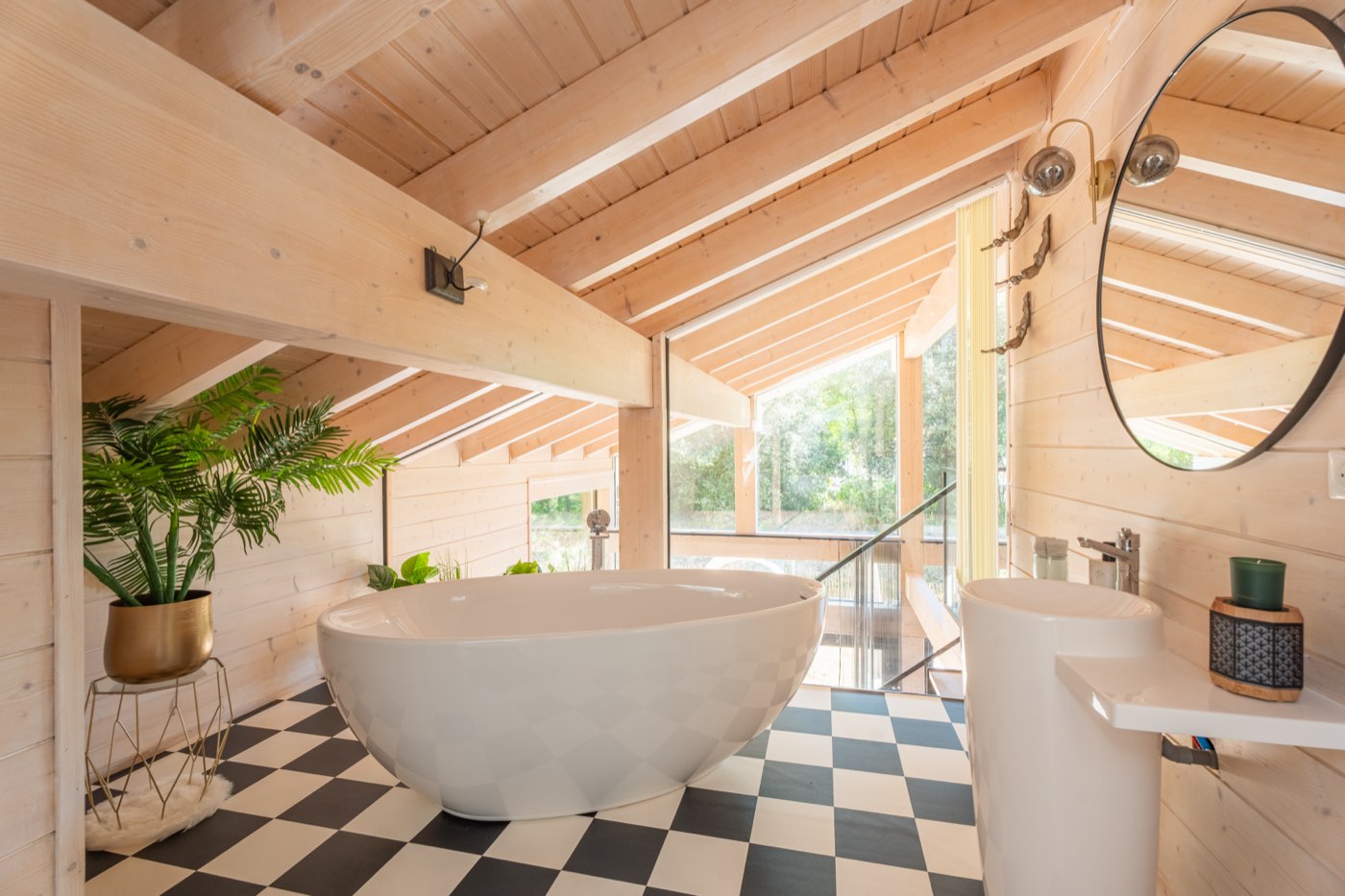 Salle de bains familiale à l'étage avec baignoire îlot, sol damier noir et blanc et vasque colonne sous charpente